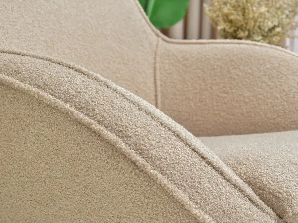 Beżowy fotel wypoczynkowy: harmonia stylu i komfortu w salonie dzięki tkaninie boucle i dębowej nodze.